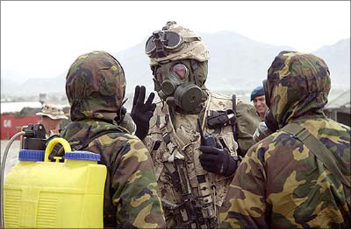 Three soldiers dressed in chemical suits.
