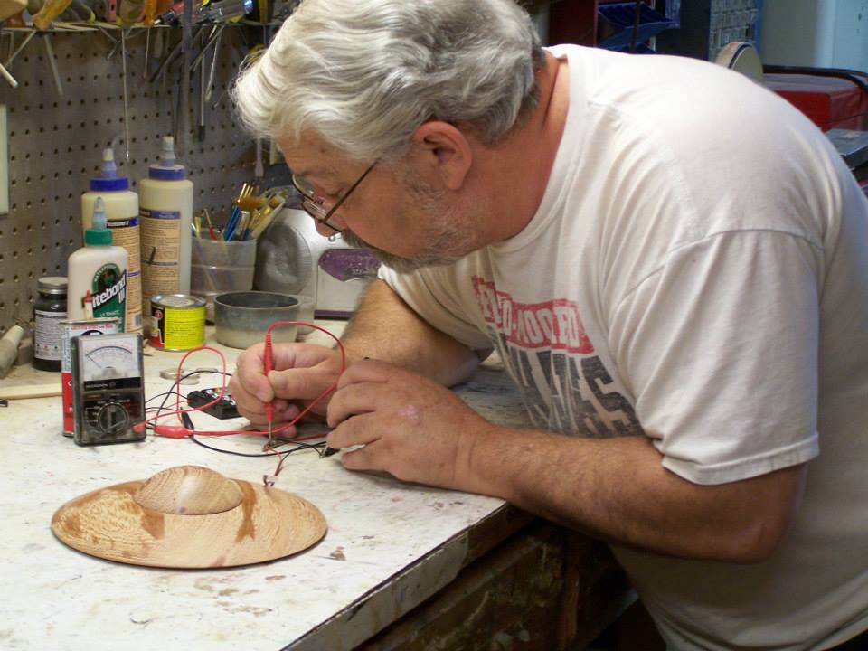 A photo of Tom Jensen working on a model of a UFO.